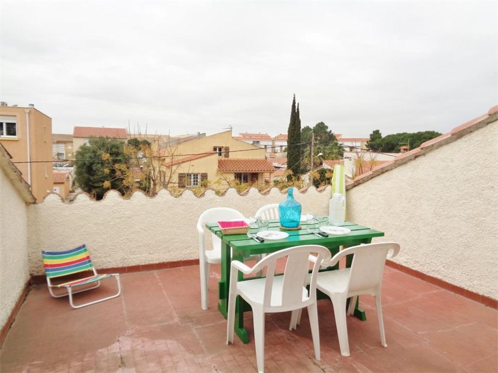 une table et des chaises vertes sur la terrasse dans l'établissement Appartement T2 avec Terrasse, Clim et Parking à 200m de la Plage - FR-1-388-114, à Argelès-sur-Mer