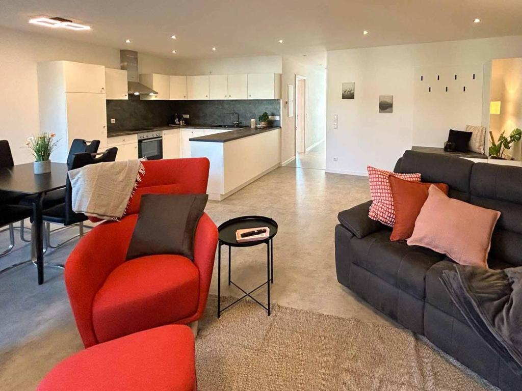 a living room with red furniture and a kitchen at Hotel und Ferienwohnungen Nebauer in Frontenhausen