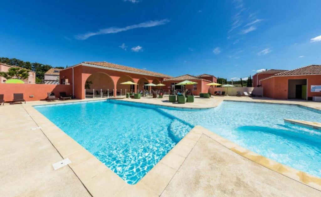 une grande piscine devant un immeuble dans l'établissement Natacha & Bacchus, à Saint-Christol