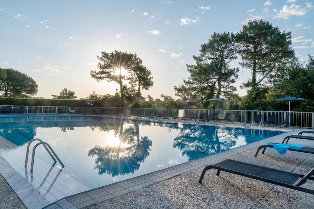 a swimming pool with two chairs and trees at Grand studio sur le golf de Chiberta in Anglet