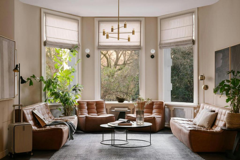 a living room with leather furniture and windows at Park House Hotel Museum Quarter, Sonder by Marriott Bonvoy in Amsterdam