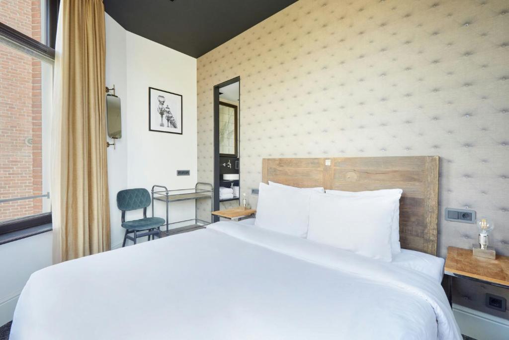 a bedroom with a large white bed and a chair at Park House Hotel Museum Quarter, Sonder by Marriott Bonvoy in Amsterdam
