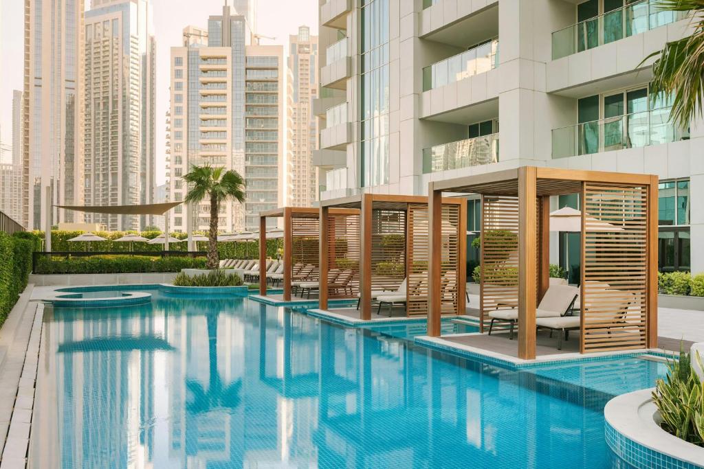 ドバイにあるSonder by Marriott Bonvoy Business Bay Apartmentsのスイミングプール(椅子付)と建物