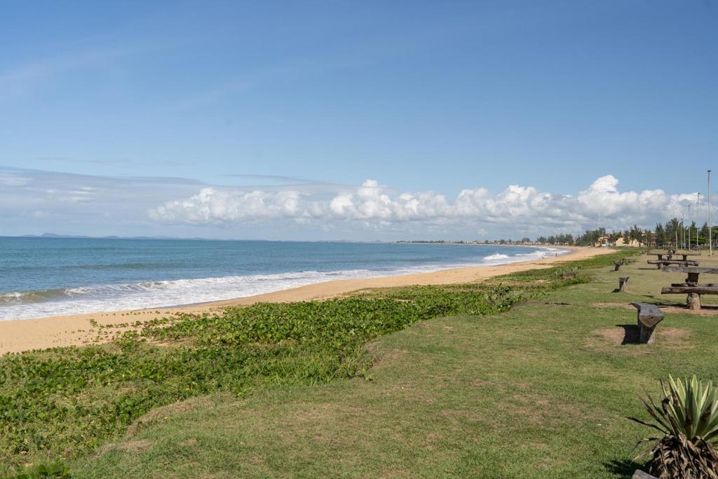 una playa con bancos y el océano en el fondo en Apto com Wi-Fi a 950m da Praia da Tartaruga, en Rio das Ostras