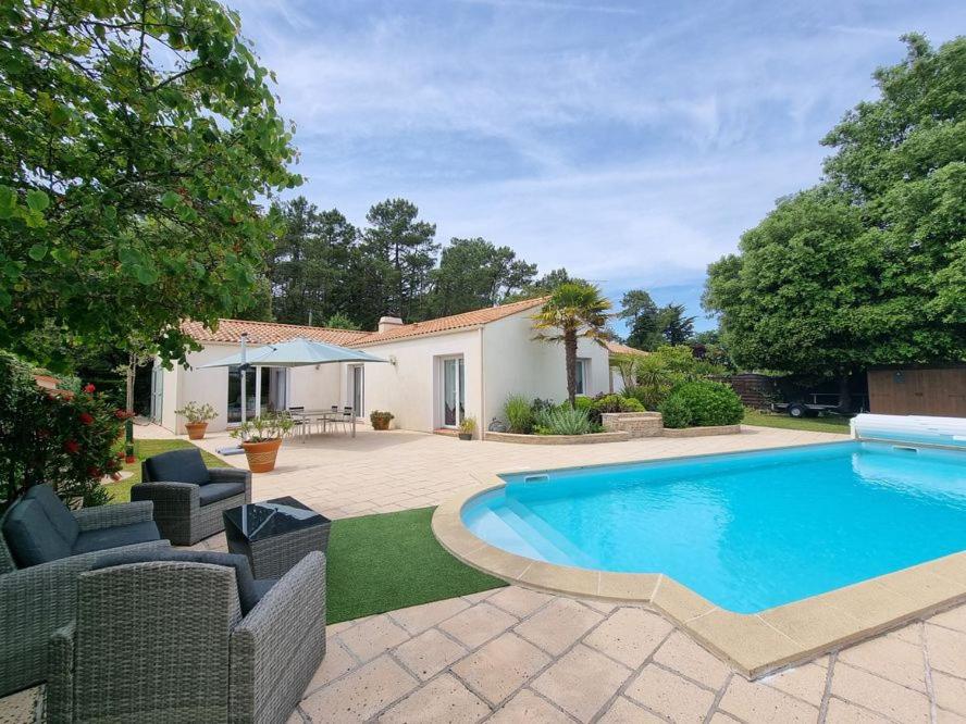 une piscine dans une cour avec des chaises et une maison dans l'établissement Maison piscine chauffée joli jardin paysagé, à Saint-Jean-de-Monts