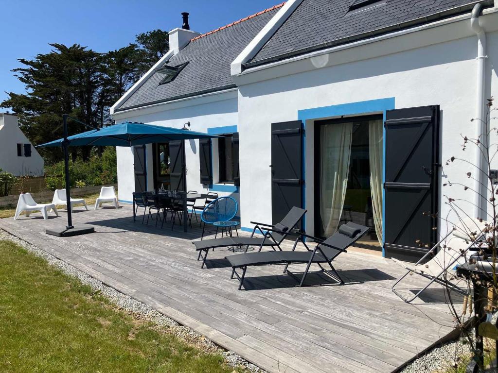 une terrasse avec des chaises et des parasols sur une maison dans l'établissement Maison indépendante à Pouldon, proche plage, 4 chambres, jardin - FR-1-418-262, à Locmaria