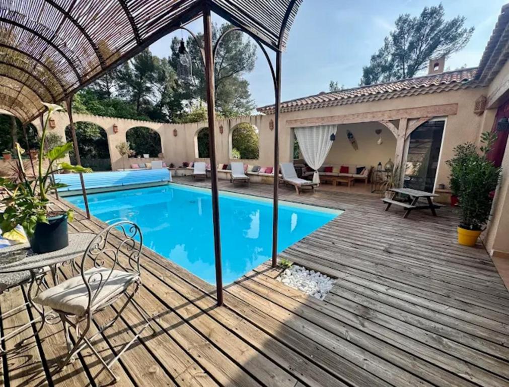 un patio avec une piscine et une terrasse en bois dans l'établissement Mas Provençal 8 pers climatisé, 3 chambres avec salles de bains, piscine privée, à Évenos