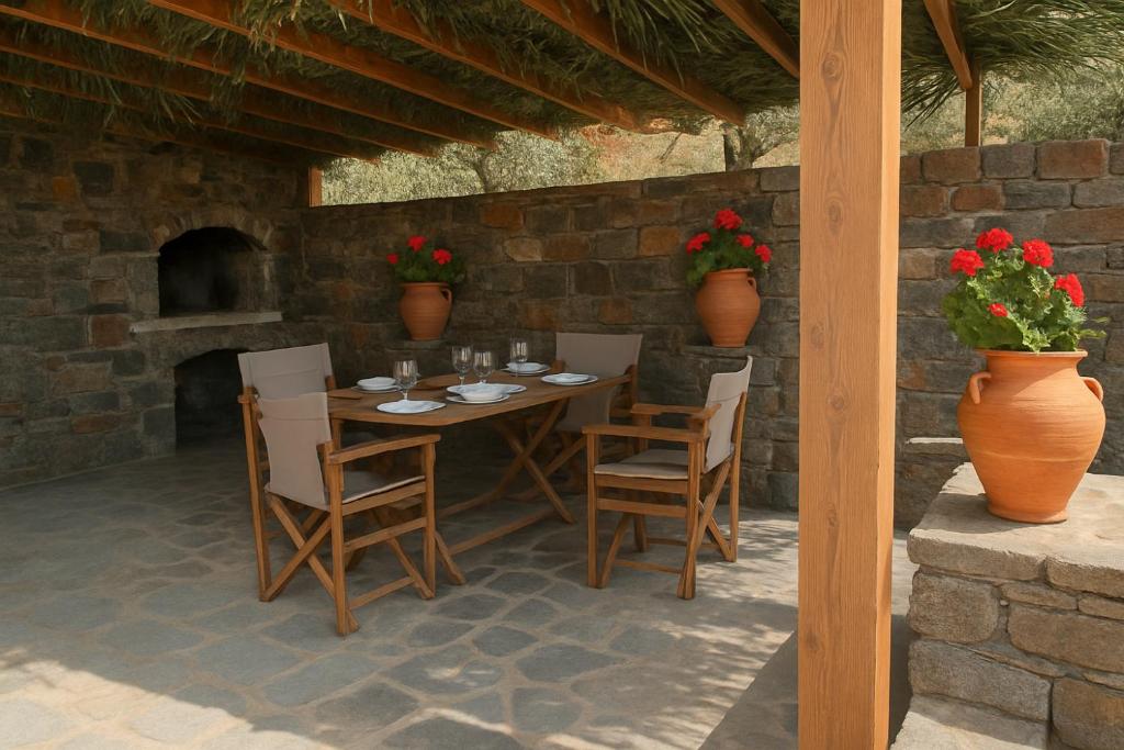 a wooden table and chairs and a brick wall at Houses at Chrisopigi Sifnos in Chrisopigi