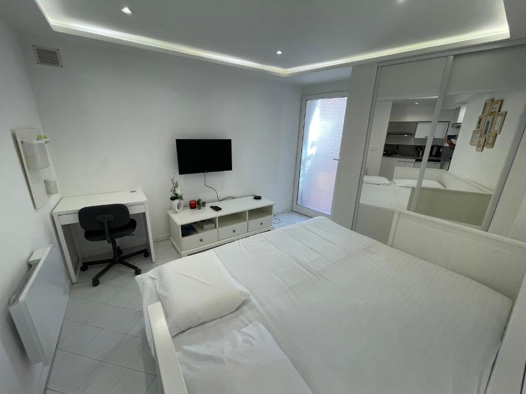 - une chambre blanche avec un lit, un bureau et une télévision dans l'établissement Old town room 100m from beach, à Menton
