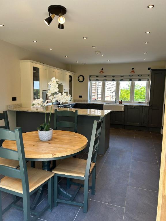 a kitchen with a wooden table and chairs and a counter at Fallow View - Luxury Countryside Cottage in Coughton
