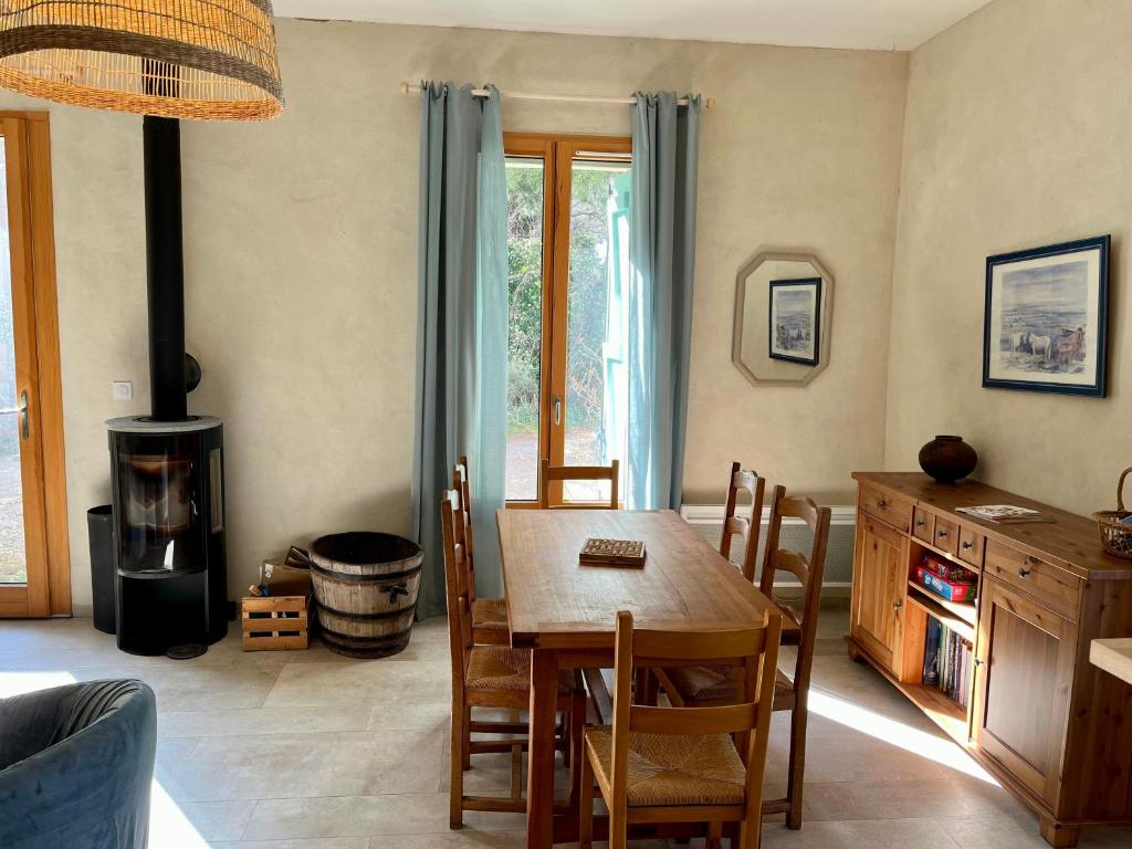 ein Esszimmer mit Tisch und Holzofen in der Unterkunft Charming House In An Organic Wine Estate in Frontignan