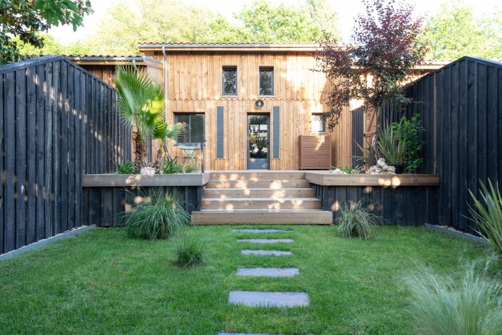 une arrière-cour avec une clôture en bois et une maison dans l'établissement Maisons PontCanal, 2 villas réunies au bord du canal à Cazaux, à La Teste-de-Buch