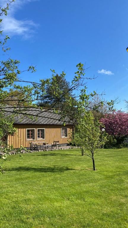uma cabana de madeira num campo relvado com uma árvore em Paulinas Hallandslänga Vid Åkulla Bokskogar em Tvååker