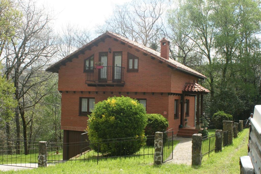 a brick house with a fence in front of it at Casa de Robles Cantabria, en el corazón de los Valles Pasiegos in Sel de la Carrera