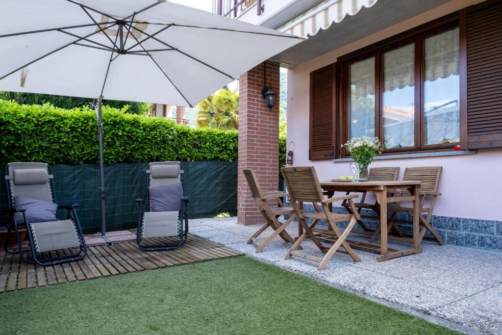 Un patio con una mesa y sillas y una sombrilla. en Appartamento Margherita, en Porto Valtravaglia