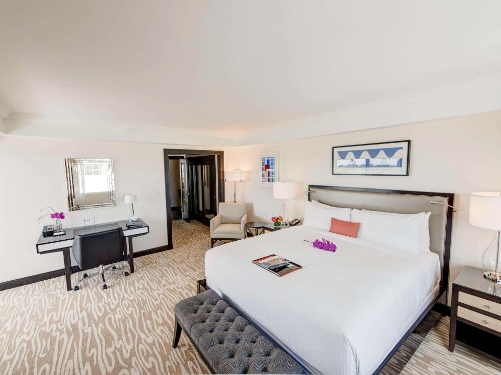 a hotel room with a large bed and a desk at Hamilton Princess & Beach Club A Fairmont Managed Hotel in Hamilton