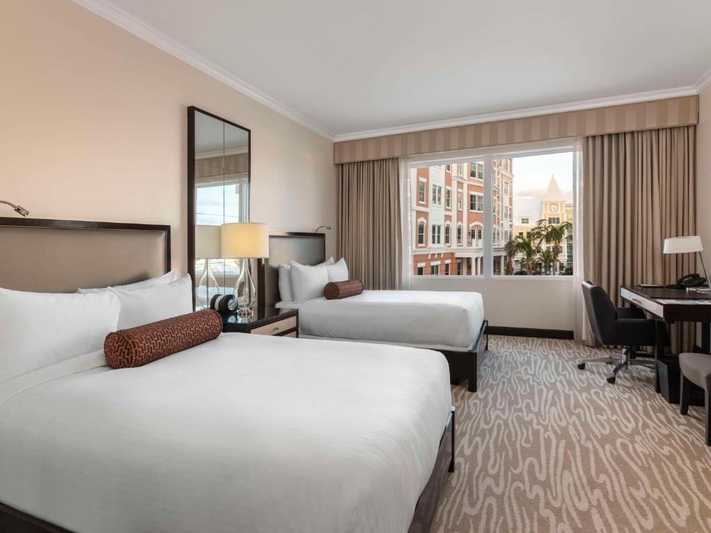 a hotel room with two beds and a desk at Hamilton Princess & Beach Club A Fairmont Managed Hotel in Hamilton
