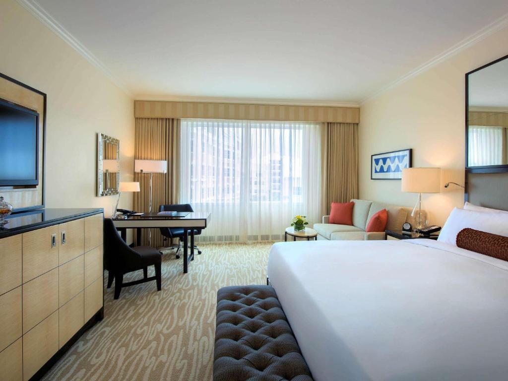 a hotel room with a large bed and a desk at Hamilton Princess & Beach Club A Fairmont Managed Hotel in Hamilton