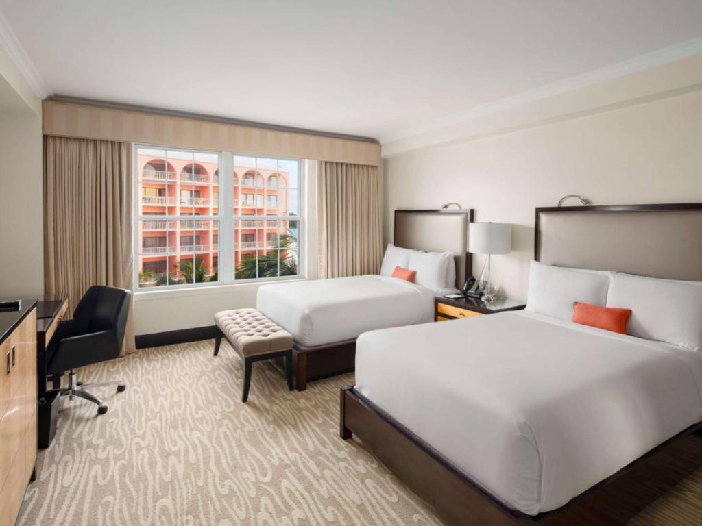 a hotel room with two beds and a desk at Hamilton Princess & Beach Club A Fairmont Managed Hotel in Hamilton