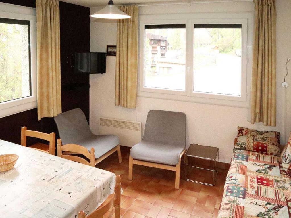 une chambre avec deux chaises, un lit et des fenêtres dans l'établissement Appt skis aux pieds avec parking, balcon, 4 lits, animaux acceptés - FR-1-322-154, aux Orres