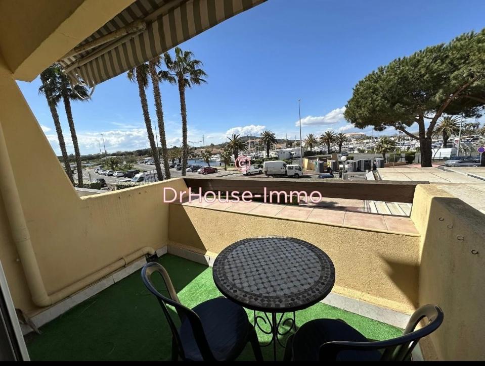 un balcon avec une table, des chaises et des palmiers dans l'établissement Village naturiste port nature 618, au Cap d'Agde