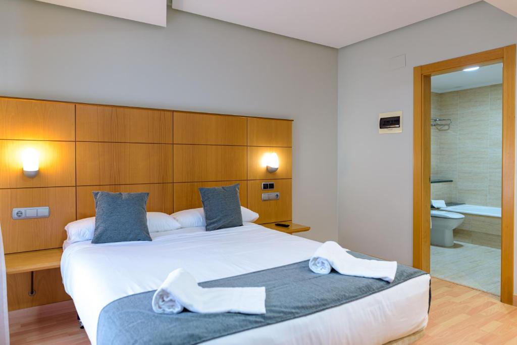 ein Schlafzimmer mit einem großen weißen Bett und ein Badezimmer in der Unterkunft Alda Xinzo in Xinzo de Limia