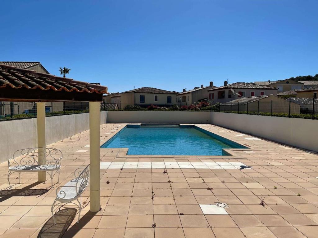 une piscine avec deux chaises et un parasol dans l'établissement T2 duplex dans résidence sécurisée, parking privé, piscine, climatisation, internet, à La Seyne-sur-Mer
