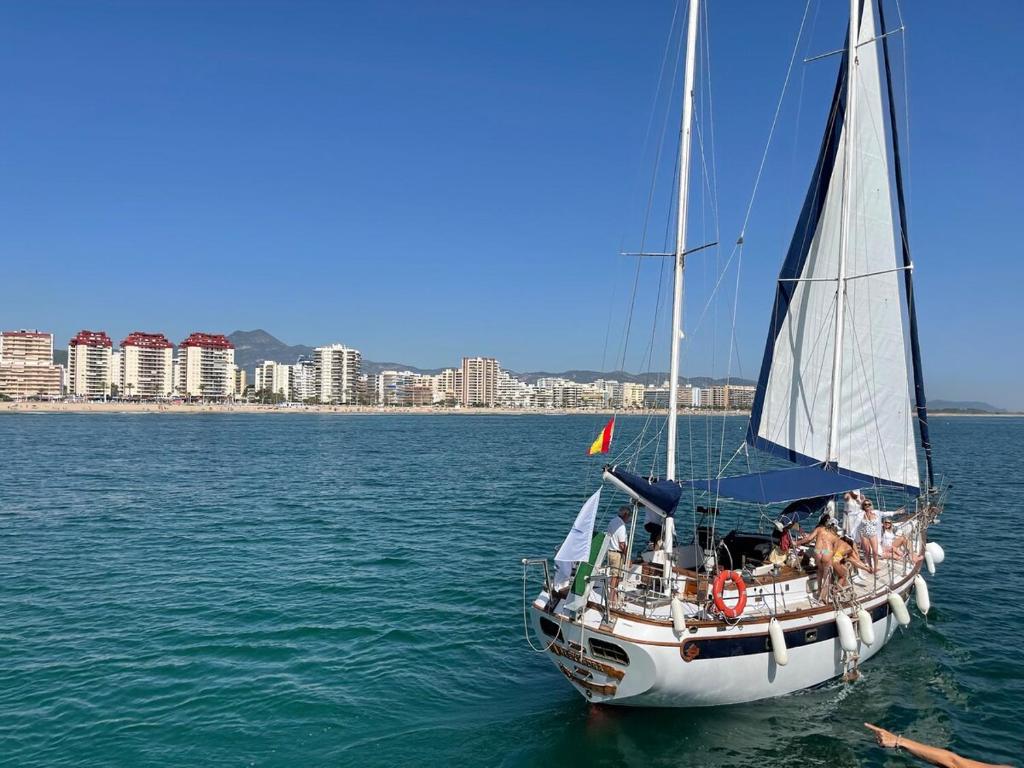 El Tiburon في Playa de Gandia: قارب شراعي في الماء مع مدينة في الخلفية