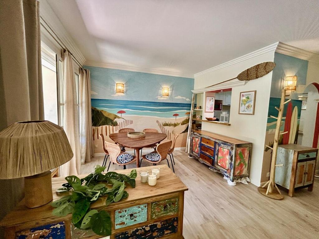 d'un salon avec une table et une peinture murale. dans l'établissement Les Restanques Maison 3 Pins, à Grimaud