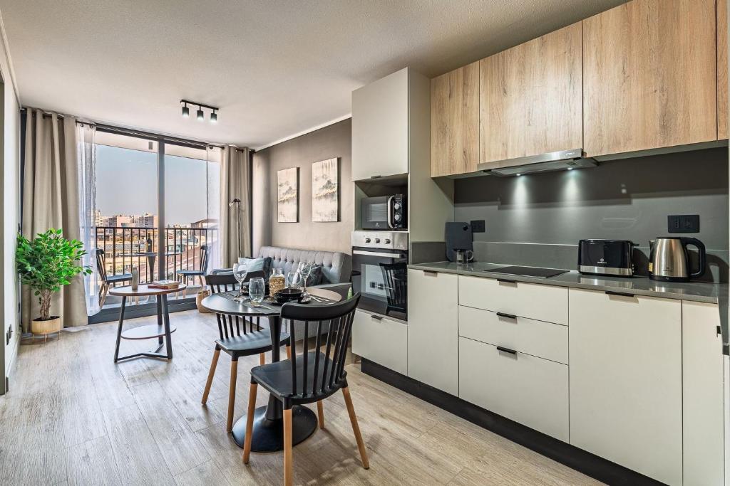 eine Küche mit weißen Schränken und einem Tisch mit Stühlen in der Unterkunft Centro Cívico - GYM - Piscina - WiFi - Terraza - Security 24-7 in Santiago