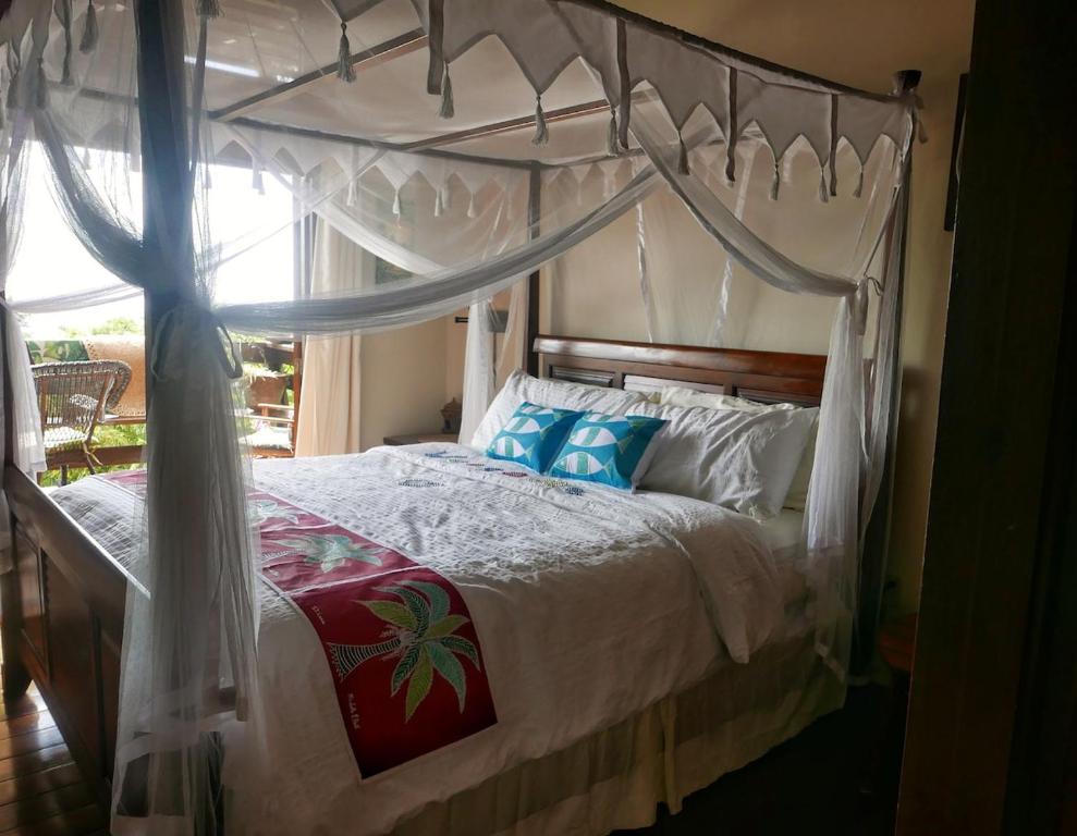 ein Schlafzimmer mit einem Himmelbett mit blauen Kissen in der Unterkunft Treehouse Hideaway Villa II - Amazing Piton Views in Soufrière