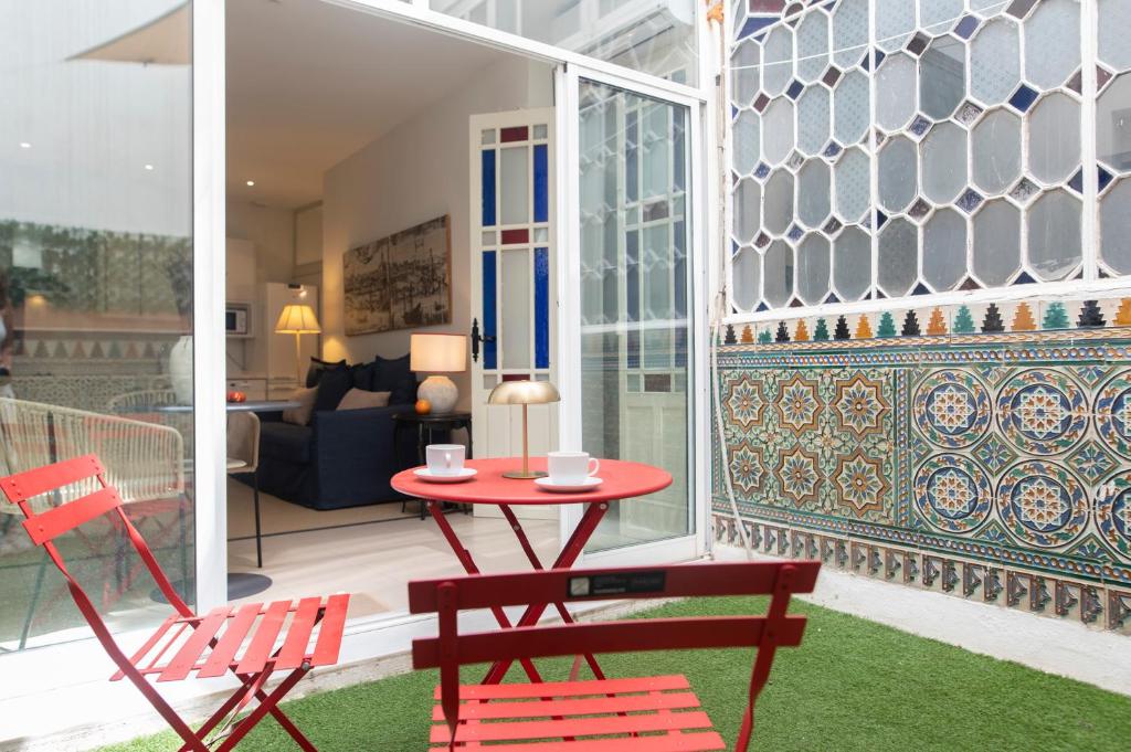 a patio with two chairs and a red table and chairs at Alohamundi Chicarreros Catedral in Seville