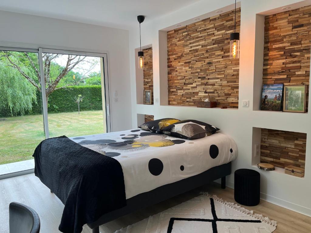 un grand lit dans une chambre avec une grande fenêtre dans l'établissement Maison au vert-Entre-Deux-Mers, Repos et confort au coeur de la nature, à Cursan