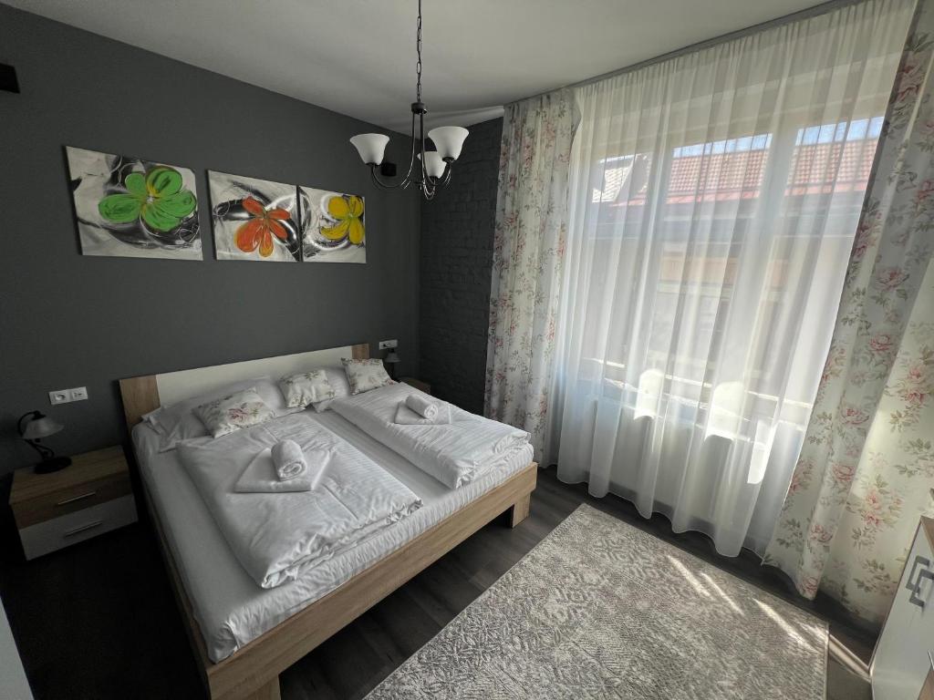 a bedroom with a bed with white sheets and a window at Karlovy Vary Cute in Karlovy Vary