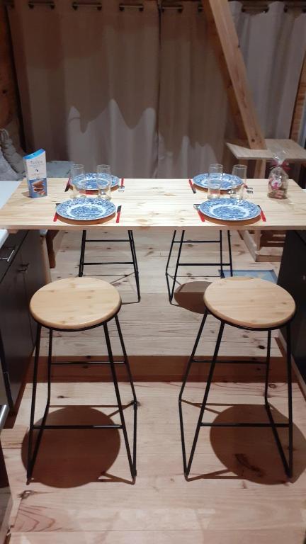 un tavolo con tre sgabelli e piatti sopra di Tiny House du Pigeonnier a Baincthun