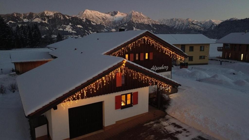 a house with christmas lights on the roof of it at Ferienhaus Alpenherz Sommer-Bergbahnen-kostenlos in Bolsterlang