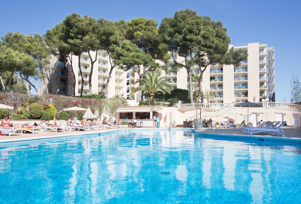 uma grande piscina num hotel com pessoas sentadas à sua volta em Grupotel Orient em Playa de Palma