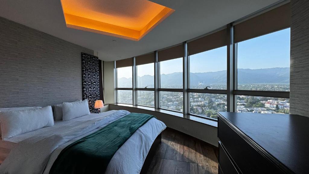 a bedroom with a large bed and large windows at Centaurus Two Bedroom Apartment in Islamabad