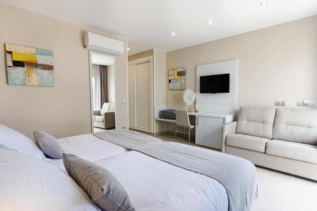 ein weißes Schlafzimmer mit einem Bett und einer Couch in der Unterkunft Sanom beach Resort by youRoom Only Adults in Maspalomas