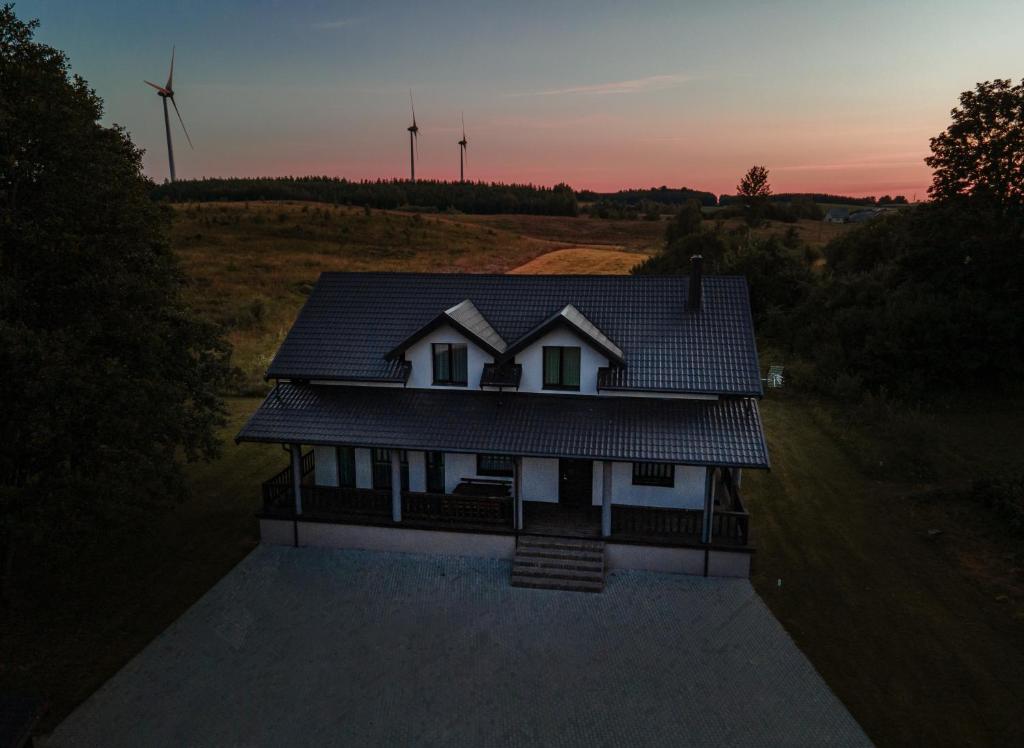 a house with a roof with wind turbines in the background at Vėjo Malūnų sodyba - Didžioji vila in Paserninkai