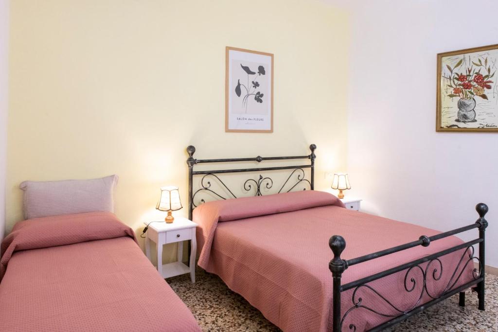 a bedroom with two beds with pink sheets at Casa Vacanza Gate Centro in Pisa