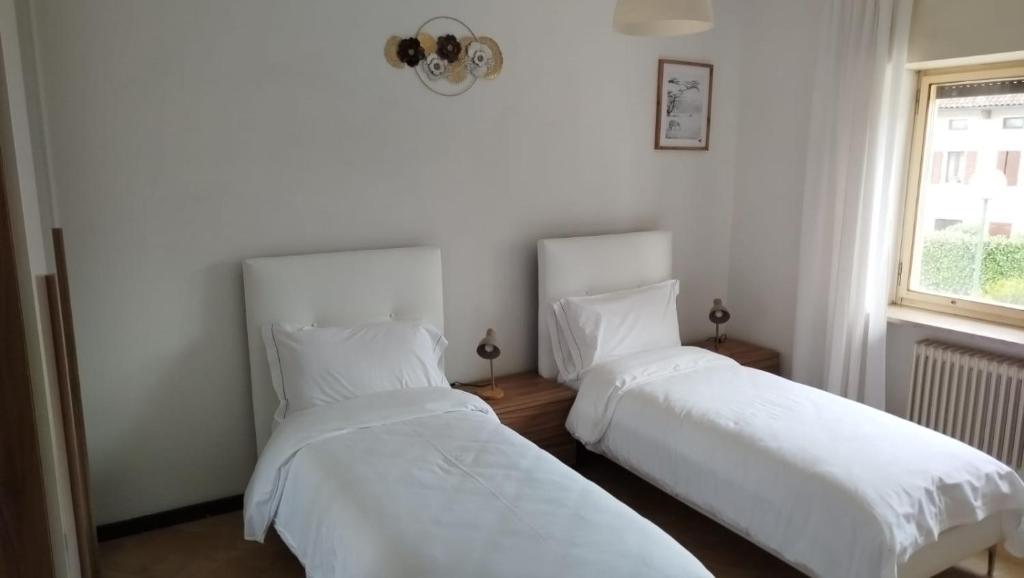two beds in a room with white sheets and a window at Locanda Antica Bribano in Sedico