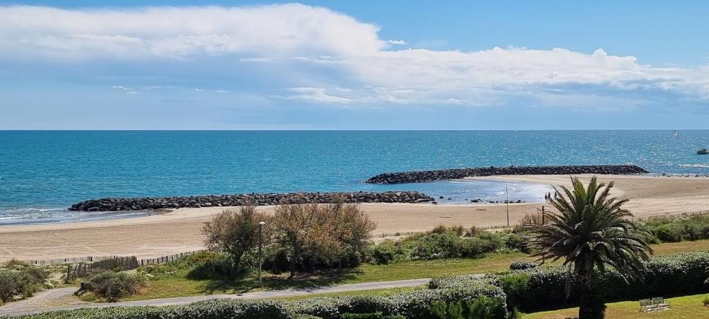 - une plage avec un mur de rochers et l'océan dans l'établissement Les Roches Marines - La Sedna - 2P4, au Cap d'Agde