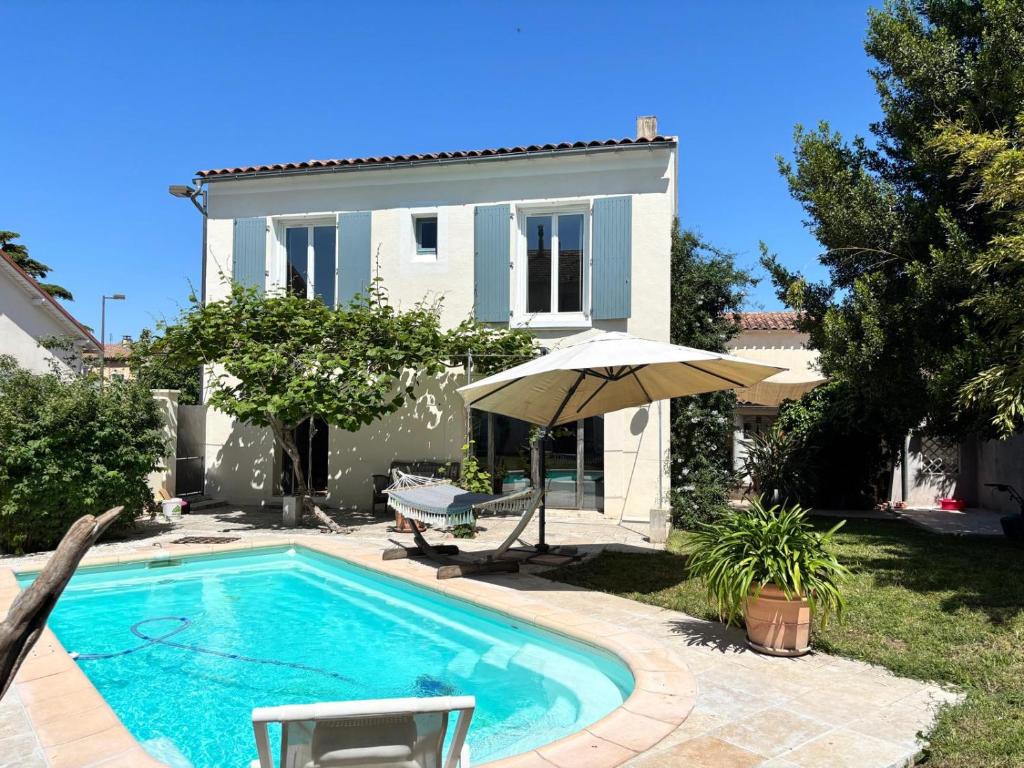 - une piscine avec un parasol en face d'une maison dans l'établissement Un paradis en provence, à Avignon