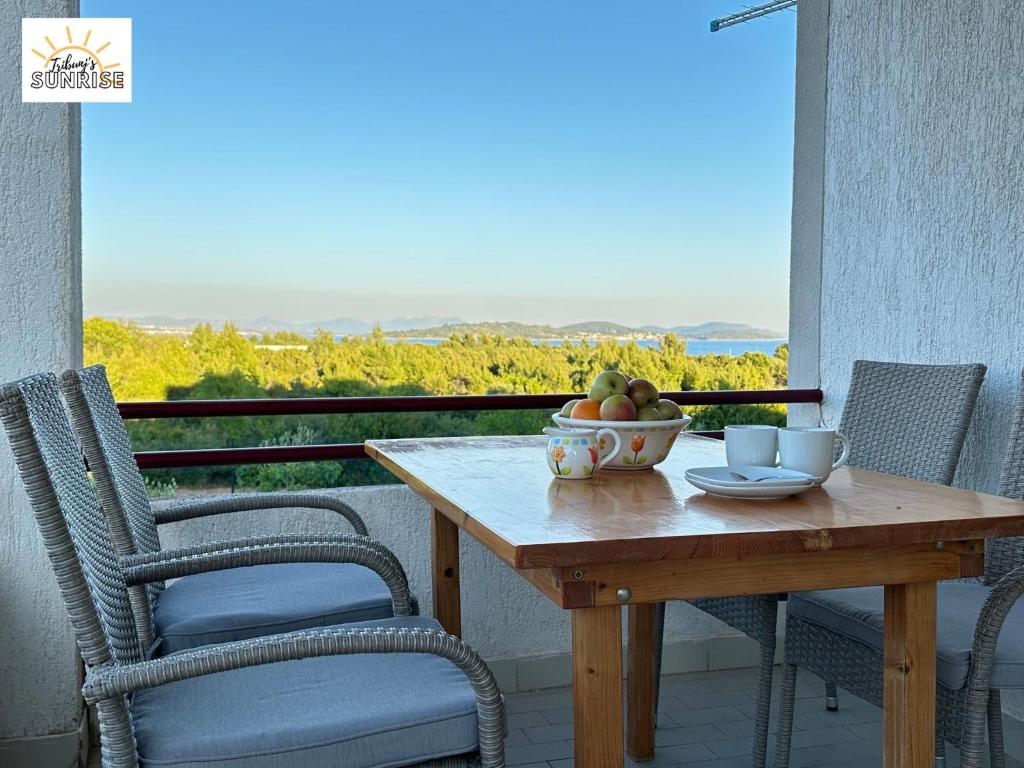 einen Holztisch mit einer Schale Obst auf dem Balkon in der Unterkunft Tribunj Sunrise in Tribunj
