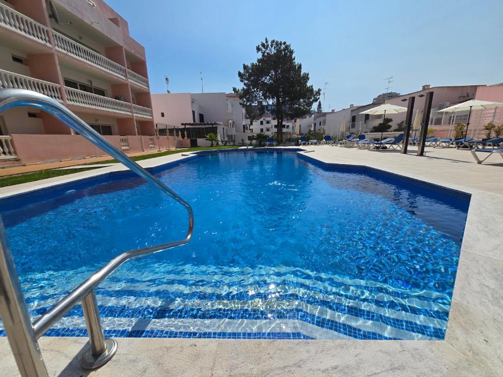 a blue swimming pool in front of a building at Monte Treasure - Beach, Wifi, Pool, Parking in Monte Gordo