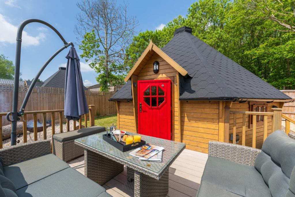 a toy dog house with a red door on a deck at Woods Meadow Glamping luxury self contained lodges in West Malling