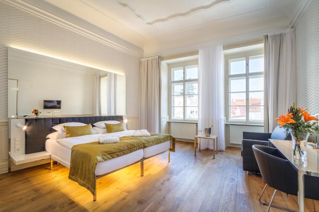 a hotel room with a bed, chair, table and window at Golden Star in Prague