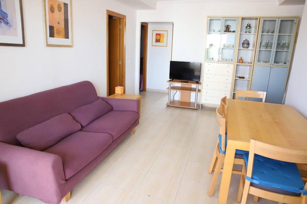 a living room with a purple couch and a table at Atico Piles in Piles