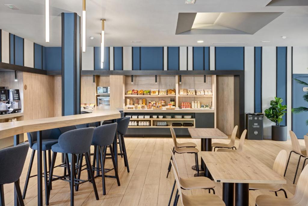 Un restaurante con mesas y sillas de madera y armarios azules. en B&B HOTEL Madrid Alcorcón, en Alcorcón